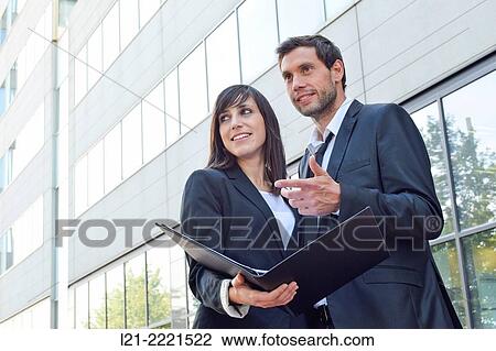 Businessman and businesswoman look over paperwork while standing outside. View Large Photo Image Stock Image - Businessman and businesswoman look over paperwork while standing outside.. Fotosearch