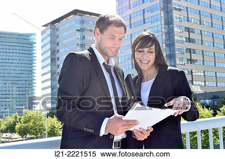 Businessman and businesswoman look over paperwork while standing outside. View Large Photo Image Stock Photography - Businessman and businesswoman look over paperwork while standing outside.. Fotosearch