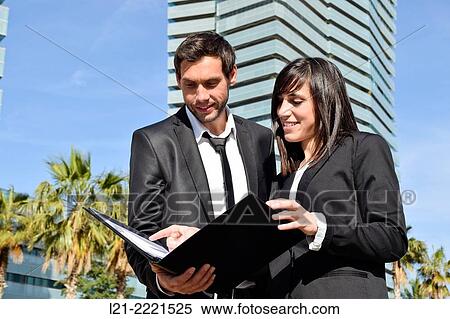Businessman and businesswoman look over paperwork while standing outside. View Large Photo Image Stock Photography - Businessman and businesswoman look over paperwork while standing outside.. Fotosearch