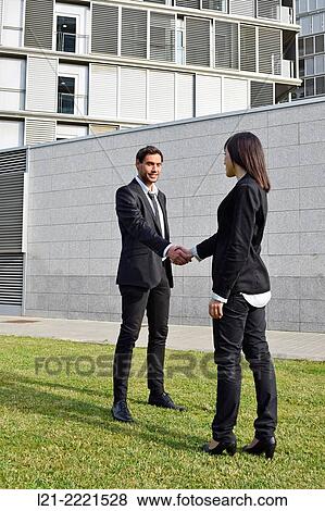 Stock Photo - Businessman and woman shaking hands outside.. Fotosearch