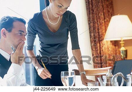 Stock Photo - Businessman and woman working in a hotel room while having breakfast. Fotosearch