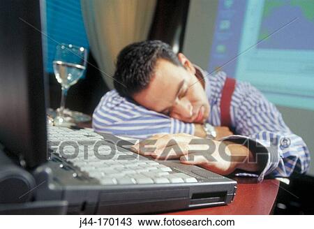 Stock Image - Businessman asleep in front of computer. Fotosearch