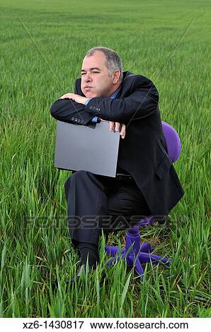businessman bored at a green field with a laptop View Large Photo Image Stock Photo - businessman bored at a green field with a laptop. Fotosearch