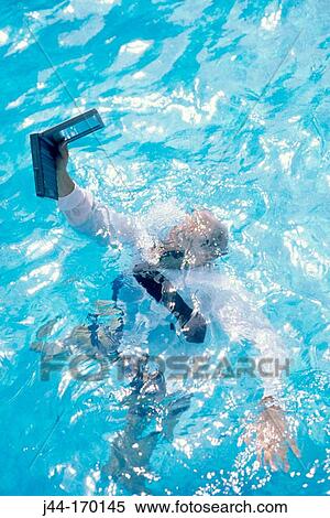 Stock Photography - Businessman drowning in pool with electronic organizer in hand. Fotosearch
