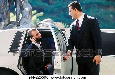 Businessman getting out of limousine while talking on cell phone View Large Photo Image Stock Photograph - Businessman getting out of limousine while talking on cell phone. Fotosearch
