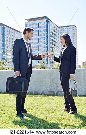 Businessman giving card presentation to businesswoman outside. View Large Photo Image Picture - Businessman giving card presentation to businesswoman outside.. Fotosearch