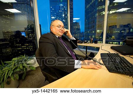 Stock Photography - Businessman in a corner office talking on the phone. Fotosearch