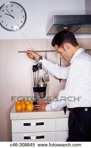 Businessman in the kitchen, squeezing oranges View Large Photo Image Stock Photography - Businessman in the kitchen, squeezing oranges. Fotosearch