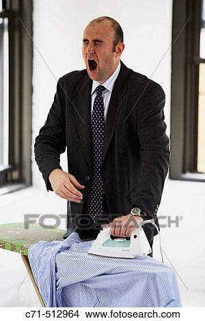Businessman ironing his clothes and yawning. View Large Photo Image Picture - Businessman ironing his clothes and yawning.. Fotosearch