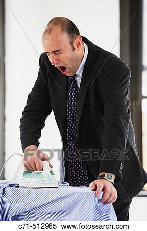 Stock Photography - Businessman ironing his clothes and yawning.. Fotosearch