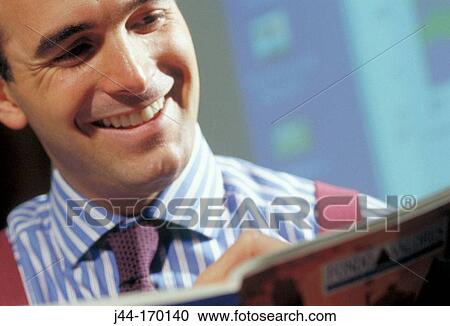 Businessman looking at a brochure smiling View Large Photo Image Stock Image - Businessman looking at a brochure smiling. Fotosearch
