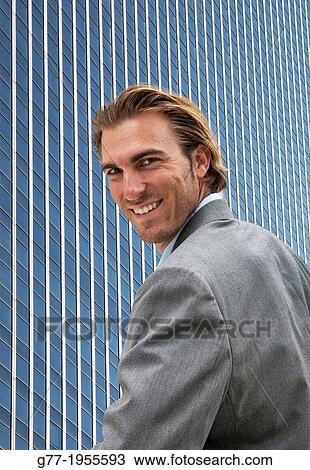 Stock Image - Businessman looking at camera under high rise building. New York. Usa.. Fotosearch