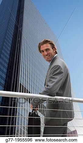 Businessman looking at camera under high rise building. New York. Usa. View Large Photo Image Stock Photograph - Businessman looking at camera under high rise building. New York. Usa.. Fotosearch