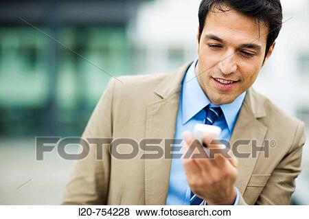 Businessman looking at his cell phone View Large Photo Image Stock Photo - Businessman looking at his cell phone. Fotosearch