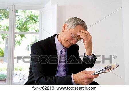 Businessman looking at papers View Large Photo Image Stock Image - Businessman looking at papers. Fotosearch