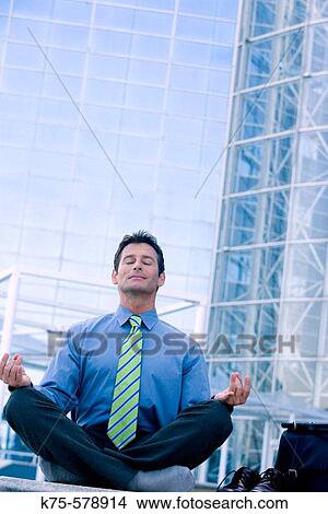 Businessman meditating outside office building View Large Photo Image Picture - Businessman meditating outside office building. Fotosearch