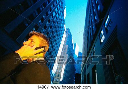 Businessman on phone in a city View Large Photo Image Stock Photo - Businessman on phone in a city. Fotosearch