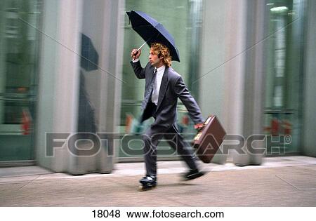 Stock Photo - Businessman on rolle blades with umbrella. Fotosearch