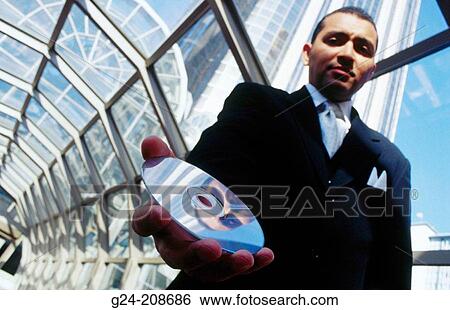 Stock Photograph - Businessman passing CD towards camera in glass tunnel. Fotosearch