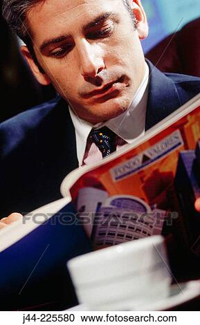 Businessman reading an annual report in the office View Large Photo Image Stock Image - Businessman reading an annual report in the office. Fotosearch