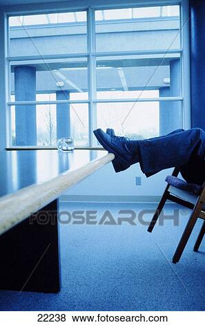 Businessman relaxing with feet up on table (toned blue) View Large Photo Image Stock Photo - Businessman relaxing with feet up on table (toned blue). Fotosearch