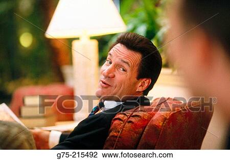 Stock Image - Businessman seated in hotel lobby. Fotosearch