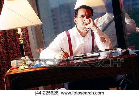 Businessman sitting on a desk in a hotel room View Large Photo Image Stock Photograph - Businessman sitting on a desk in a hotel room. Fotosearch