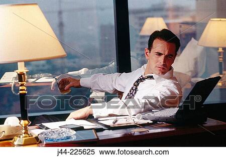 Businessman sitting on a desk working with laptop computer in a hotel room View Large Photo Image Stock Photography - Businessman sitting on a desk working with laptop computer in a hotel room. Fotosearch