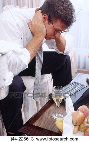 Businessman sitting on a sofa working with laptop computer and glass of wine View Large Photo Image Stock Image - Businessman sitting on a sofa working with laptop computer and glass of wine. Fotosearch
