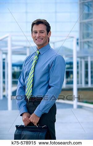 Businessman standing outside office building with briefcase View Large Photo Image Stock Photography - Businessman standing outside office building with briefcase. Fotosearch