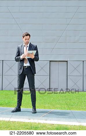 Businessman standing using a tablet. View Large Photo Image Stock Image - Businessman standing using a tablet.. Fotosearch