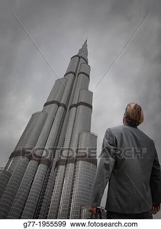 Stock Photo - Businessman under high rise building, Dubai, UAE. Fotosearch