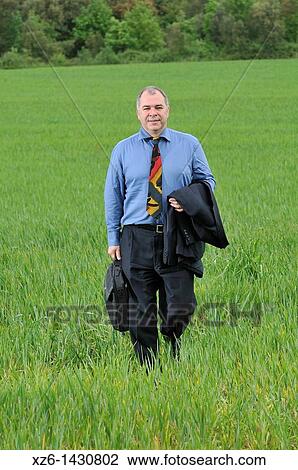 Businessman walking in the field View Large Photo Image Stock Image - Businessman walking in the field. Fotosearch
