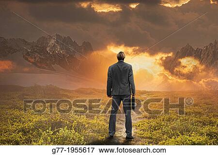 Businessman watching sunset in a mountain range. View Large Photo Image Stock Photo - Businessman watching sunset in a mountain range.. Fotosearch