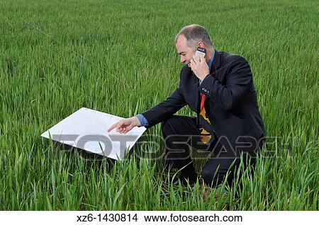 businessman with blueprints and a mobile phone in the field View Large Photo Image Picture - businessman with blueprints and a mobile phone in the field. Fotosearch