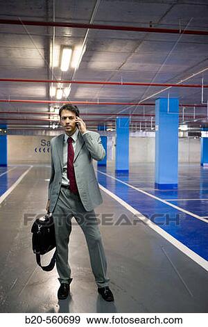 Businessman with mobile phone. Parking lot. View Large Photo Image Stock Photo - Businessman with mobile phone. Parking lot.. Fotosearch