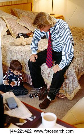 Stock Image - Businessman with son in bedroom. Fotosearch