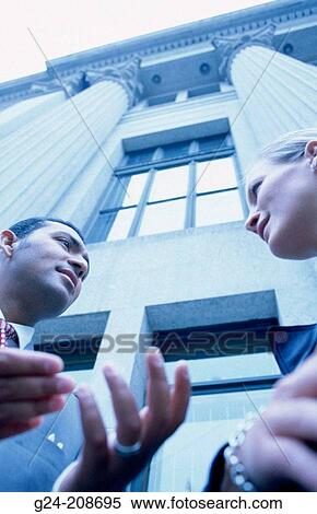 Stock Photography - Businessman & woman engaged in animated conversation. Fotosearch