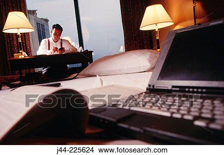 Businessman working on a desk in a hotel room at night View Large Photo Image Picture - Businessman working on a desk in a hotel room at night. Fotosearch