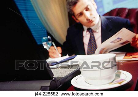 Businessman working on a desk with a cup of tea in the office View Large Photo Image Stock Image - Businessman working on a desk with a cup of tea in the office. Fotosearch