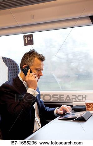 Businessman working on a tablet on a commuter train View Large Photo Image Stock Photograph - Businessman working on a tablet on a commuter train. Fotosearch