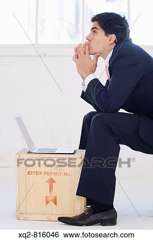 Stock Photograph - Businessman working on latop on crate. Fotosearch
