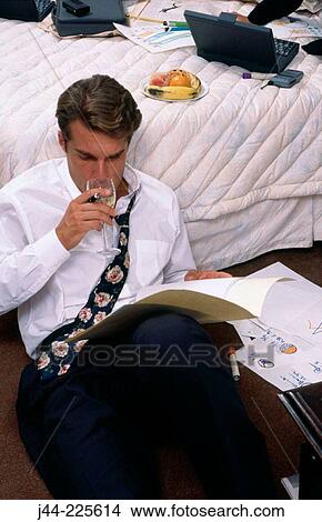 Businessman working on the floor while driking wine in a hotel room View Large Photo Image Picture - Businessman working on the floor while driking wine in a hotel room. Fotosearch