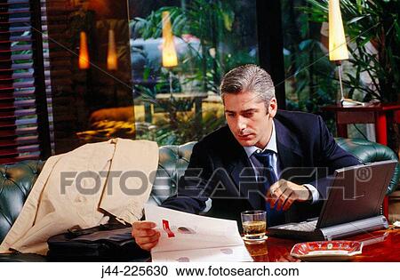 Stock Image - Businessman working with laptop computer in a hotel lounge. Fotosearch