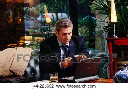 Businessman working with laptop computer in a hotel lounge View Large Photo Image Stock Image - Businessman working with laptop computer in a hotel lounge. Fotosearch