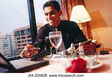 Businessman working with laptop computer on a table in a hotel room View Large Photo Image Stock Photo - Businessman working with laptop computer on a table in a hotel room. Fotosearch