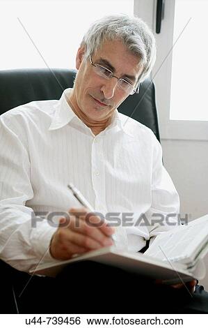 Businessman writing in his notebook View Large Photo Image Stock Photograph - Businessman writing in his notebook. Fotosearch