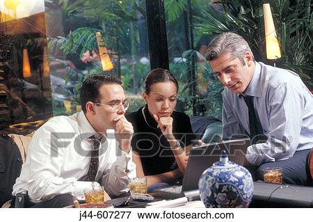 Businessmen and woman working with lap top in a hotel lobby View Large Photo Image Stock Photo - Businessmen and woman working with lap top in a hotel lobby. Fotosearch