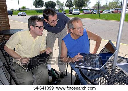 Businessmen conduct an informal business meeting using laptop computers outside a restaurant View Large Photo Image Stock Photo - Businessmen conduct an informal business meeting using laptop computers outside a restaurant. Fotosearch