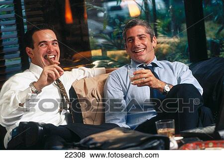 Stock Photo - Businessmen having drink and cigar in a hotel lounge. Fotosearch